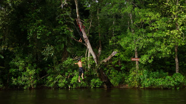 Boy Hanging Onto Rope Swing Falls Into River