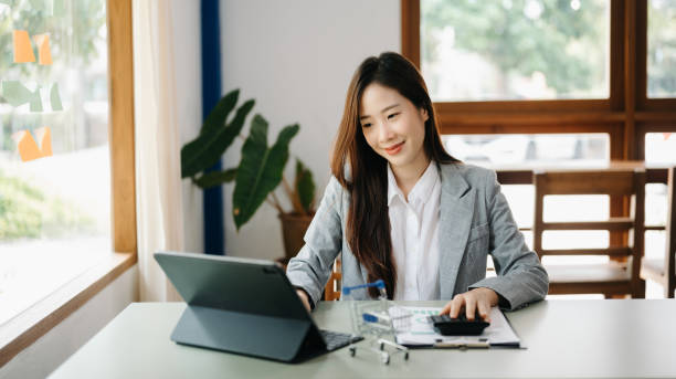 istock Young beautiful woman using laptop and tablet while sitting at her working place. Concentrated at work. 1473887960