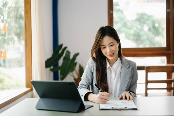 istock Young beautiful woman using laptop and tablet while sitting at her working place. Concentrated at work. 1473887973