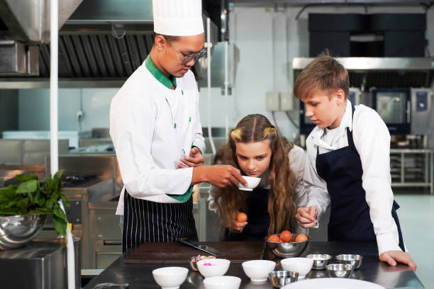 istock Chef teacher teaches cooking to the group children in class kitchen room.  Chef preparing student for learning marking and cooking food at workshop.  Education Concept 1473892307