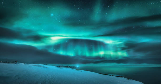 aurora boreal sobre o oceano. luzes do norte e costa marítima congelada - noruega do norte - fotografias e filmes do acervo