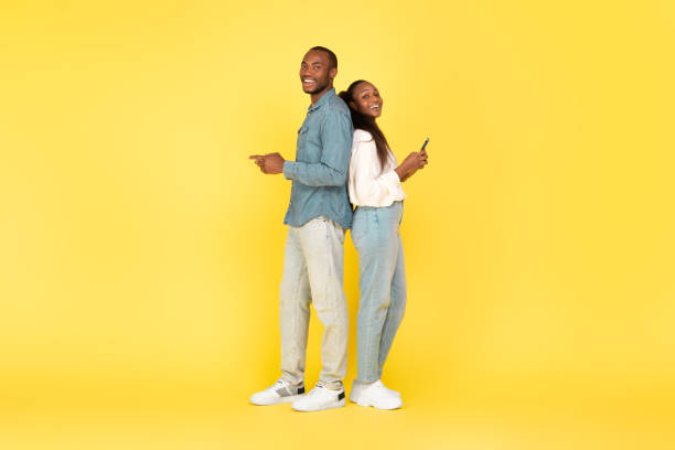 istock African American Couple Using Mobile Phones Texting Over Yellow Background 1473893138