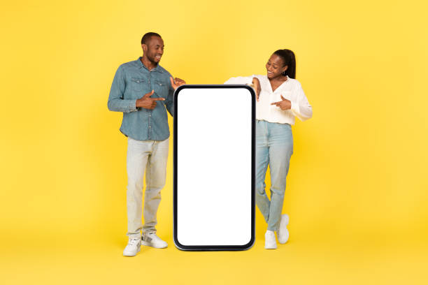istock Black Couple Pointing At Big Smartphone Blank Screen, Studio Shot 1473893143