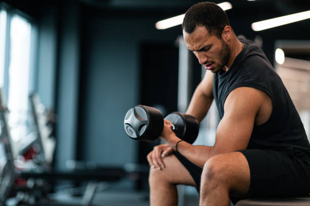 istock Young Black Male Athlete Training With Dumbbell, Making Seated Biceps Curl 1473893184