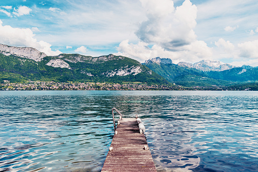Wooden jetty and view of Lake Annecy - Haute-Savoie, France. Lake Annecy (French: Lac d'Annecy) is a perialpine lake in Haute-Savoie in France. It is named after the city of Annecy.It is the third-largest lake in France and it is known as \
