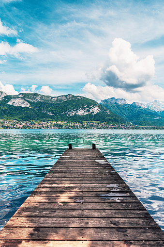 Wooden jetty perspective and beautiful view of Lake Annecy. Lake Annecy (French: Lac d'Annecy) is a perialpine lake in Haute-Savoie in France. It is named after the city of Annecy.It is the third-largest lake in France and it is known as 