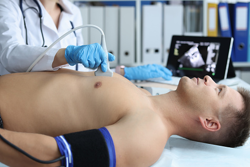 Doctor places ultrasound probe on chest of male patient. Medical examination of the work of heart and cardiology