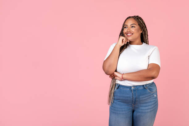 African Plus Size Lady Looking Aside Standing Over Pink Background stock photo