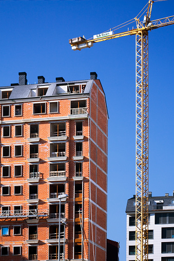 Lugo, Spain_  March 21, 2011: Large apartment building construction site, high section, construction crane .Galicia, Spain. Clear blue sky background.