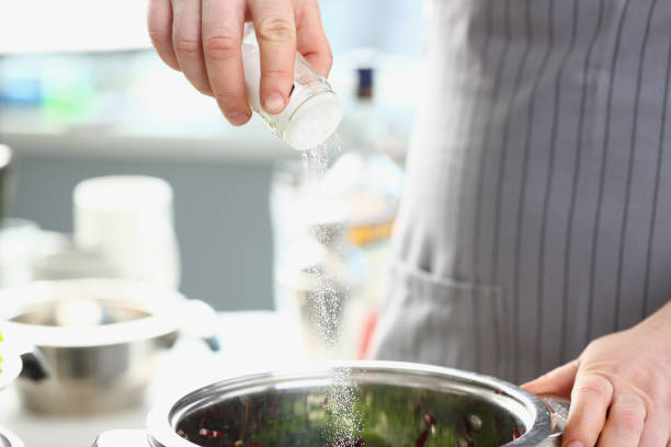 istock Cook pours salt into pan in kitchen 1473895016