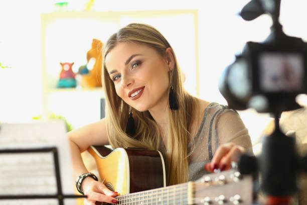 istock Blonde woman playing guitar live on camera 1473898787