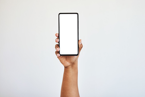 Teléfono sostenido de la mano, pantalla en blanco con maqueta y manos de mujer negra en el estudio aisladas sobre fondo blanco. Tecnología, conectar y hacer zoom en el espacio en el teléfono inteligente para el sitio web, las redes sociales o la publici photo