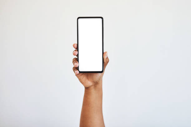 전화기를 들고 있는 손, 모형이 있는 빈 화면, 흰색 배경에 격리된 스튜디오에 있는 흑인 여성의 손. 기술, 웹 사이트, 소셜 미디어 또는 광고를위한 스마트 폰의 공간 연결 및 확대 - holding hands 뉴스 사진 이미지