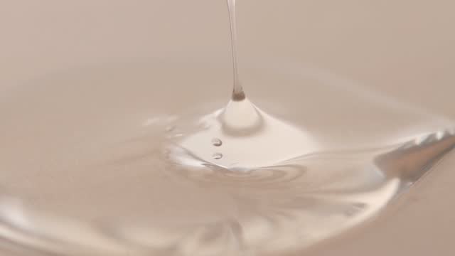 Cosmetic gel, hyaluronic acid in a glass pipette on a beige background, macro. Beauty concept.