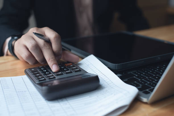 istock Businessman, accountant using calculator to calculate business report and budget document with laptop computer on table at office 1473904507