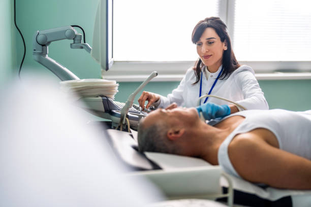Female doctor examining a patient's neck by using an ultrasound equipment stock photo