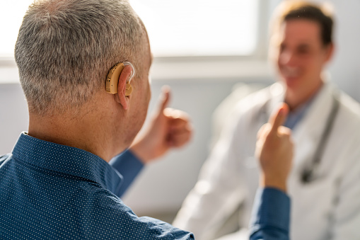 Mature patient with hearing aid showing thumb up to his doctor.
