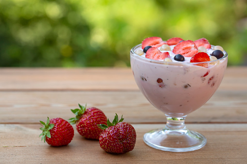 Yogurt with summer berries on a wooden table. Healthy food rich in fiber, vitamins and antioxidants.