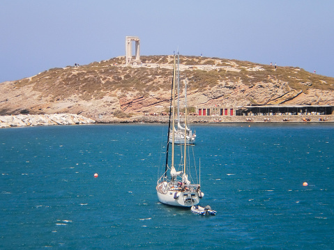 Anchored sailboat in the bay. View of an anchored white sailboat near the coast of the greek island of Naxos. Greece