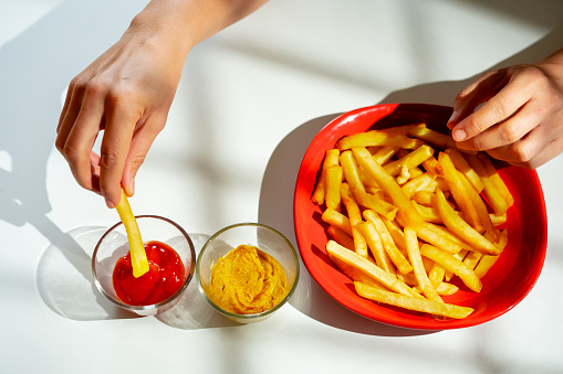 Dipping French fries into a ketchup bowl