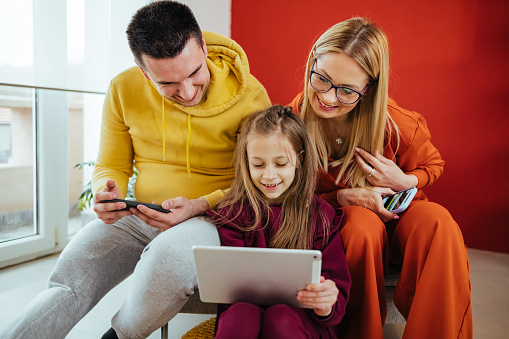 Relaxed  family using wireless technology at home.