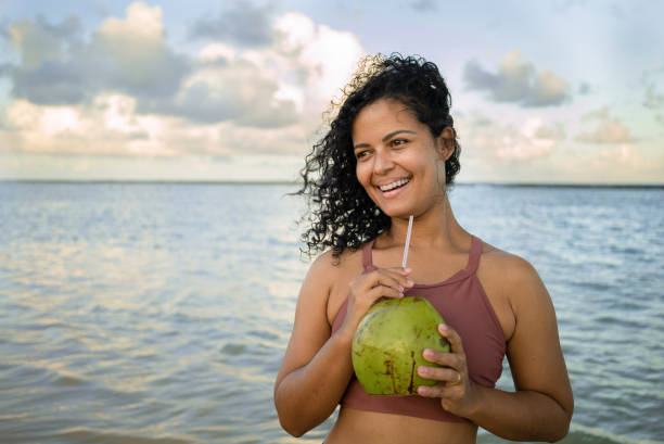 istock Woman drinking coconut water on the beach 1473914117