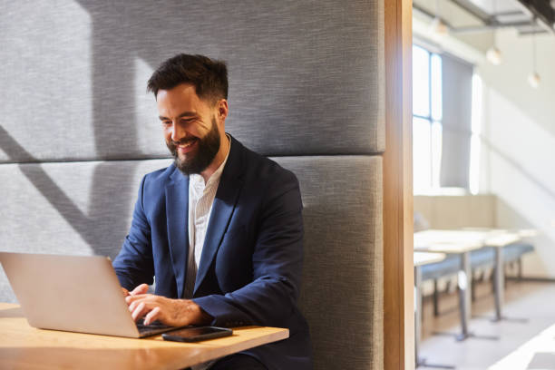 istock Smiling young businessman working on his laptop in a modern office 1473916329