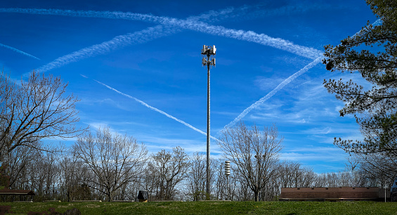 On a bright, sunny winter day in Veterans Park in Lexington, Kentucky, the vapor trails from airplanes formed a precise rhombus shape in the sky behind a 5G cellphone tower.