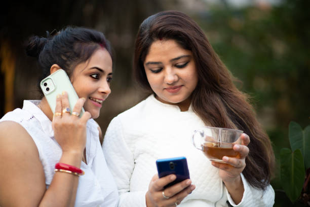 istock Two married Women are  talking and gossiping on mobile while drinking  tea in a garden 1473920069