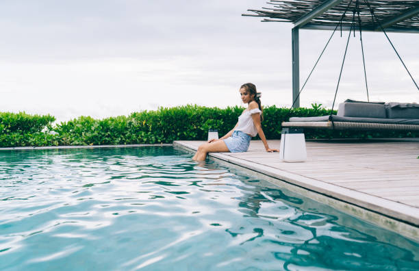istock Dreamy ethnic female tourist chilling at poolside 1473921356