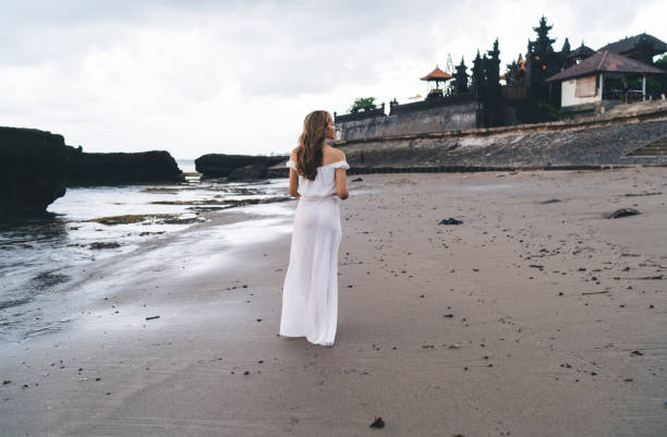 istock Unrecognizable woman walking along sandy shore 1473921407