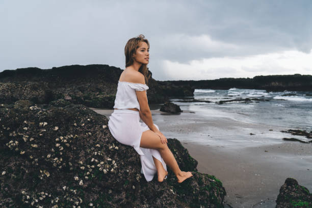 istock Sensual woman sitting on stone cliff 1473921433