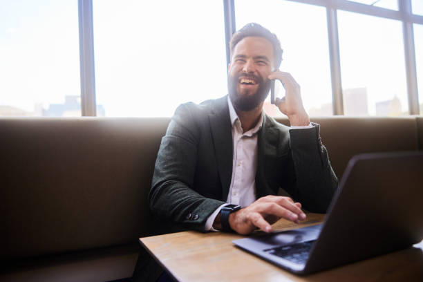 istock Laughing young businessman talking on his phone while working in an office lounge 1473923121