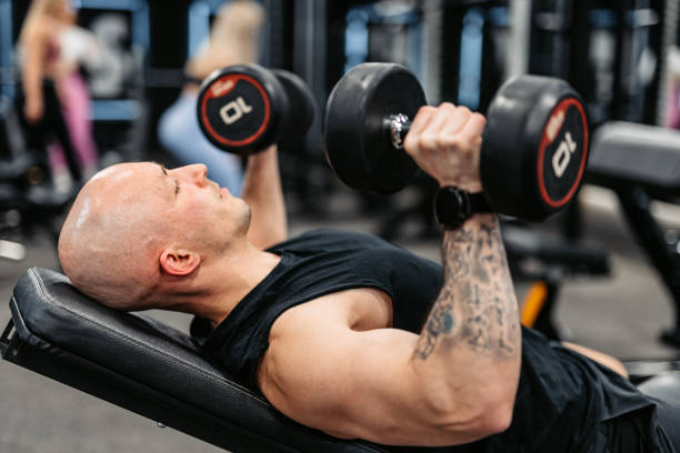 istock Young Man Training With Dumbbells At The Gym 1473923544