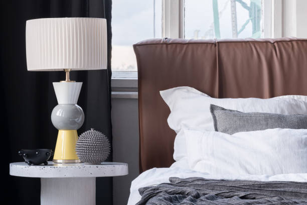 istock Elegant lamp on bedside table next to cozy bed 1473926892