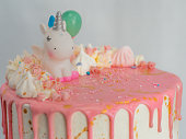 pink frosted dripping icing white birthday cake cake with unicorn , meringue and sprinkles toppers, finished with golden brush strokes