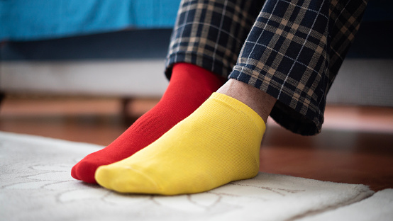 Man in pajamas with red and yellow socks stepping on the carpet