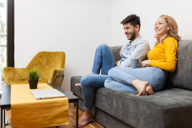 istock couple in love on a sofa watching tv and smiling 1473930122