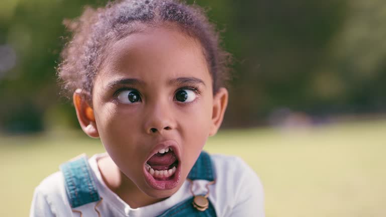 Silly, goofy and portrait of a child in nature showing an expression, funny face and crazy. Young, comic and girl doing weird facial expressions for fun, playing and comedy in a garden with mockup