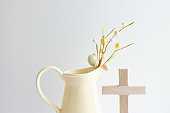 istock Cross and yellow pitcher with easter eggs on branch 1473934452