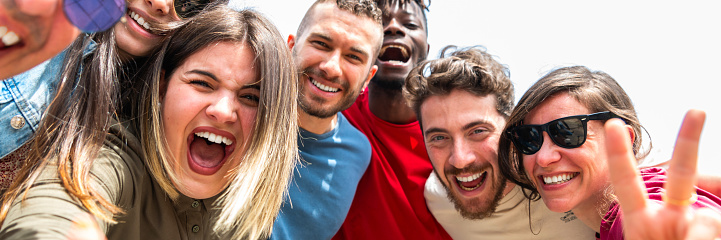 Group happy multiracial friends taking selfie in outdoors with mobile phone – diverse young people hugging selfie in outside with smartphone – horizontal web banner size for header