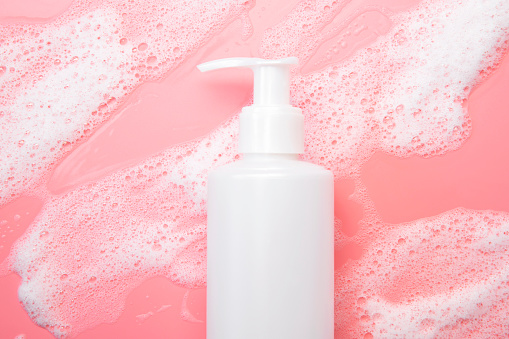 Cosmetic template mockup. White plastic bottles with air foam on pink background. Face wash, mousse, soap, shampoo, shower gel. Beauty, spa, skin care, cosmetic product top view flat lay