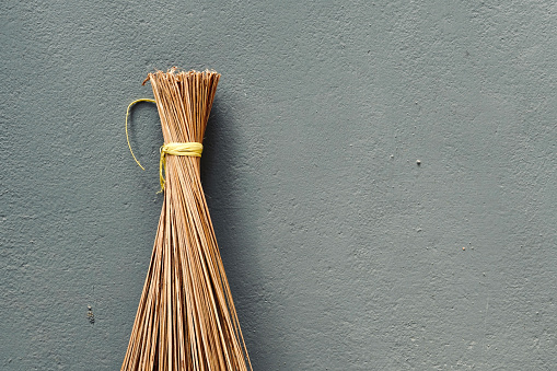 Traditional cleaning broom stick isolated against wall. It is used in India from olden days.