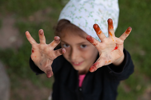 Smiling child showing her hands in paint, focus on the hands