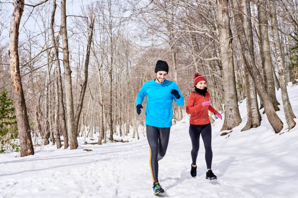 istock Cheerful couple running amidst leafless trees 1473950447