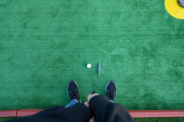Top view of a unrecognizable woman golfer playing miniature golf