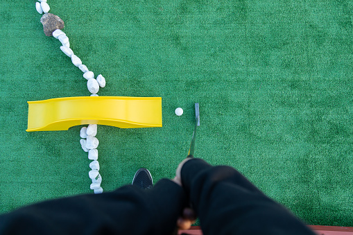 Top view of a unrecognizable woman golfer playing miniature golf