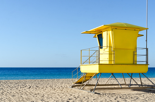 yellow lifeguard booth on the beach of the canary islands. it is a clean beach, there are no people and the sky is clear of clouds.