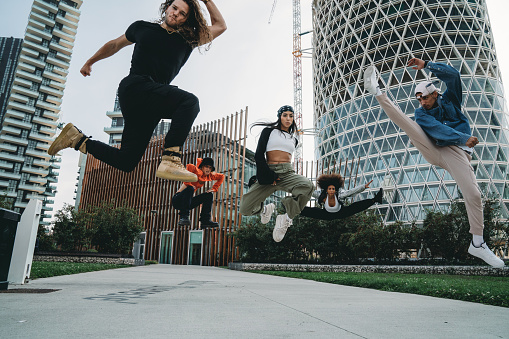 Five cool friends are jumping in a modern location. They are dancers. Multi ethnic group of people.