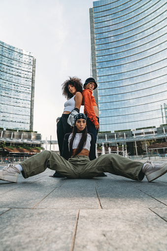 Three female dancer friends are posing in a modern city. Cool attitude. Multi ethnic group of people.